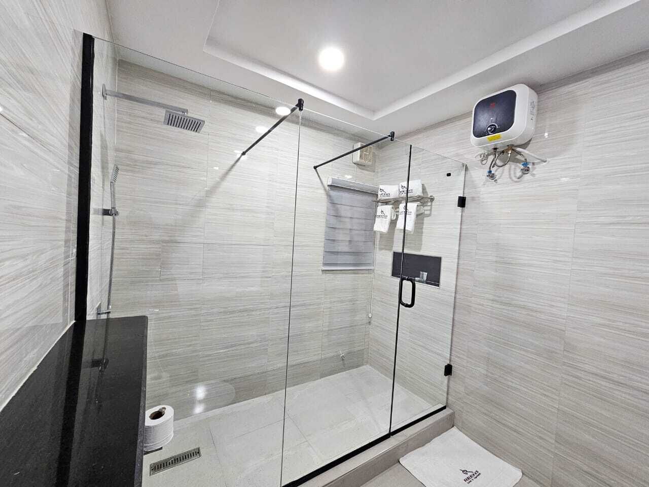 A modern bathroom with a glass-enclosed shower, a black countertop, and a wall-mounted air purifier.