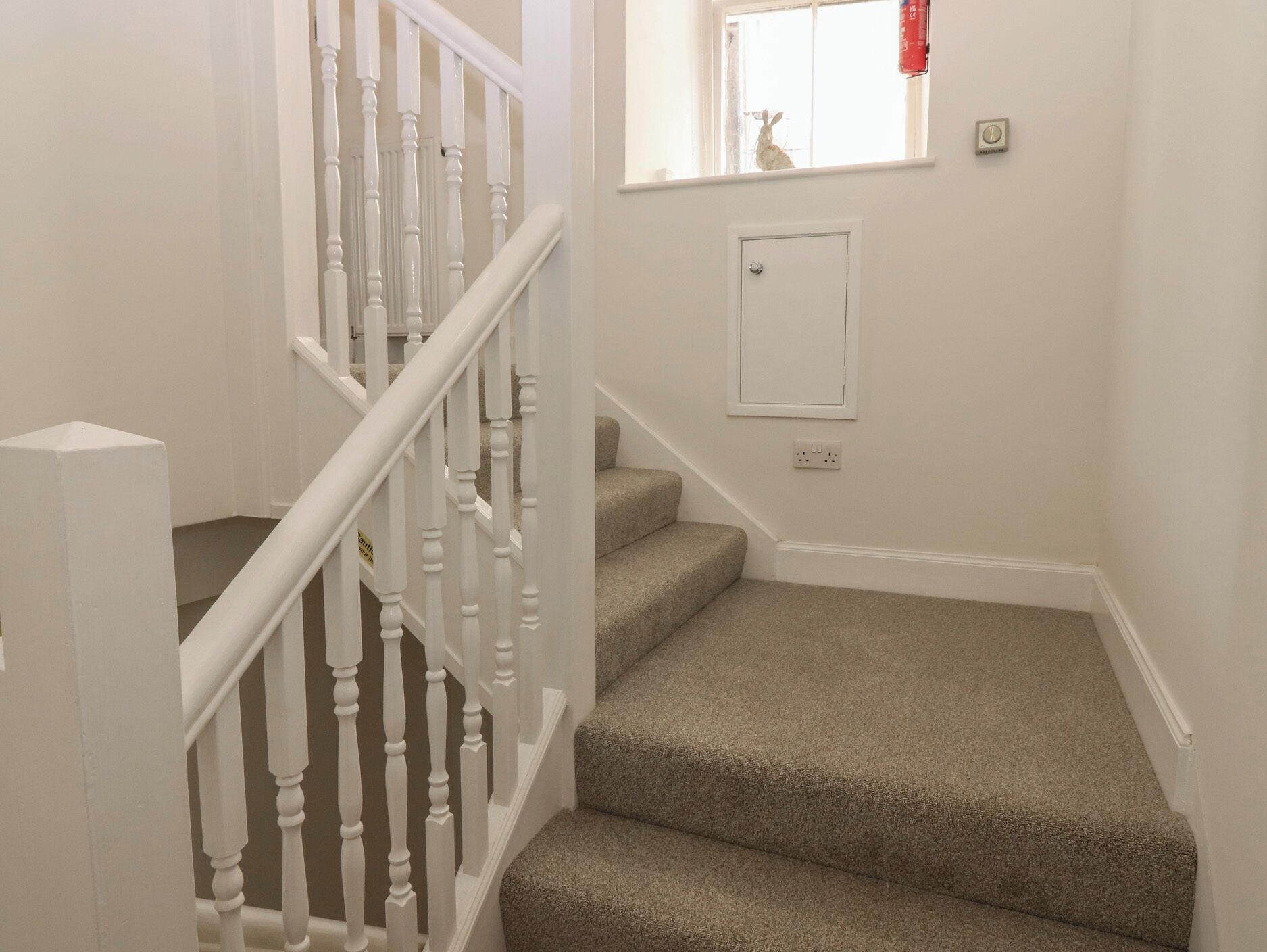 A staircase with white balusters and beige carpeted steps.
