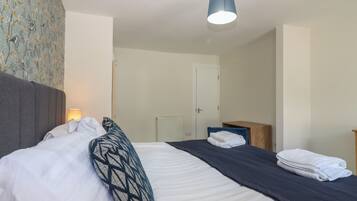 Een hotelkamer met een bed, een bedlampje, een houten nachtkastje en een deur.