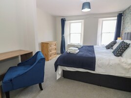 Quarto com cama, escrivaninha, cadeira e cômoda.