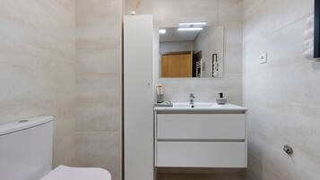 A modern bathroom with a toilet, a sink with a mirror above it, and a towel rack on the wall.