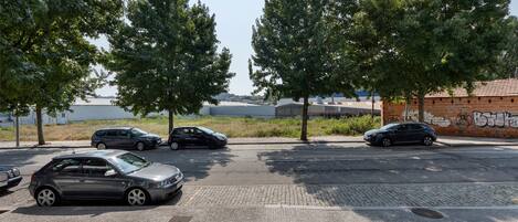A parking lot with cars, trees, and a building with graffiti.