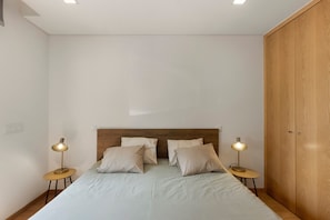 Une chambre à coucher avec un lit, deux lampes de chevet, une armoire en bois et une table ronde.