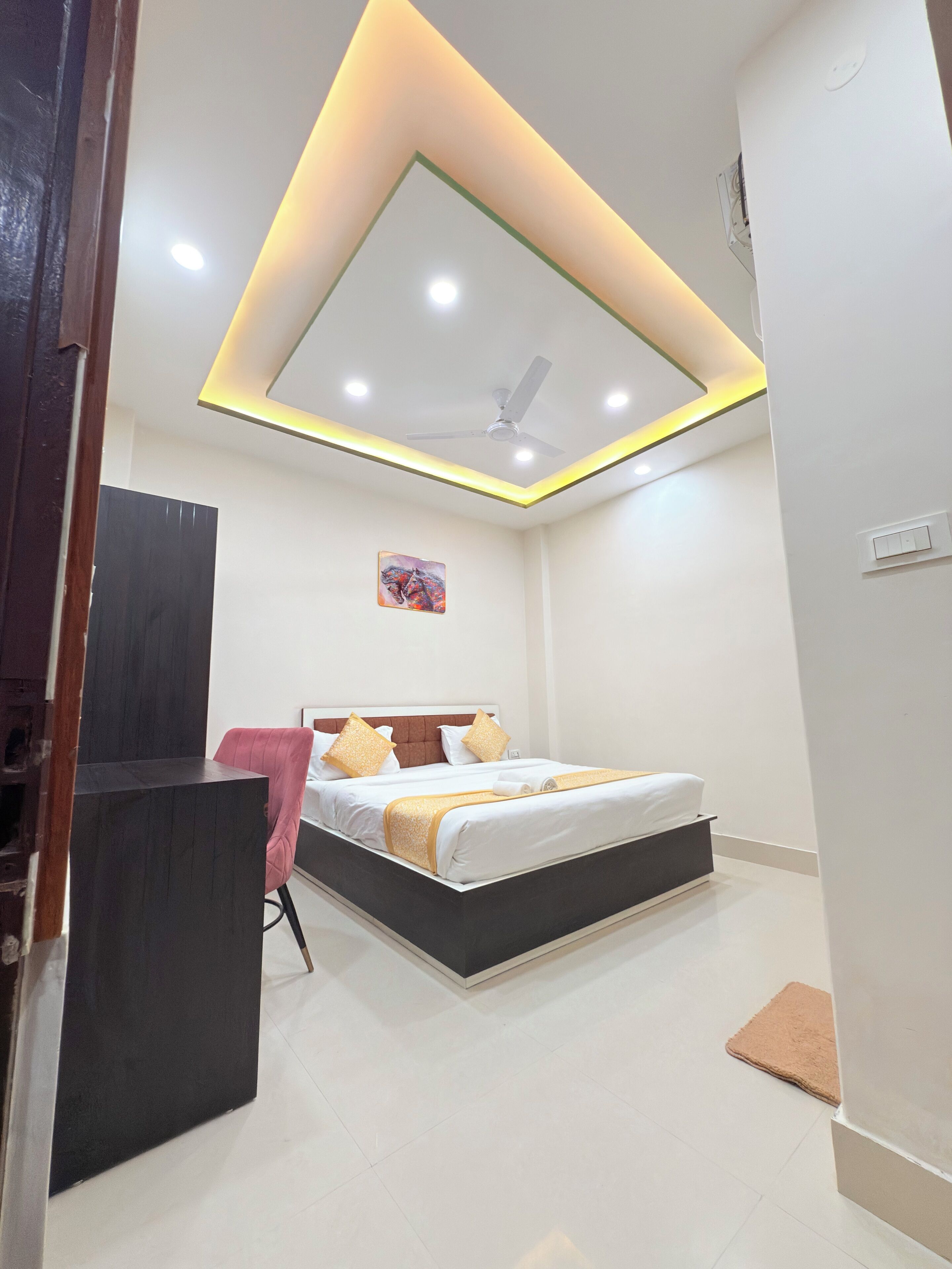 Une chambre à coucher avec un lit, un bureau, une chaise et un ventilateur de plafond.