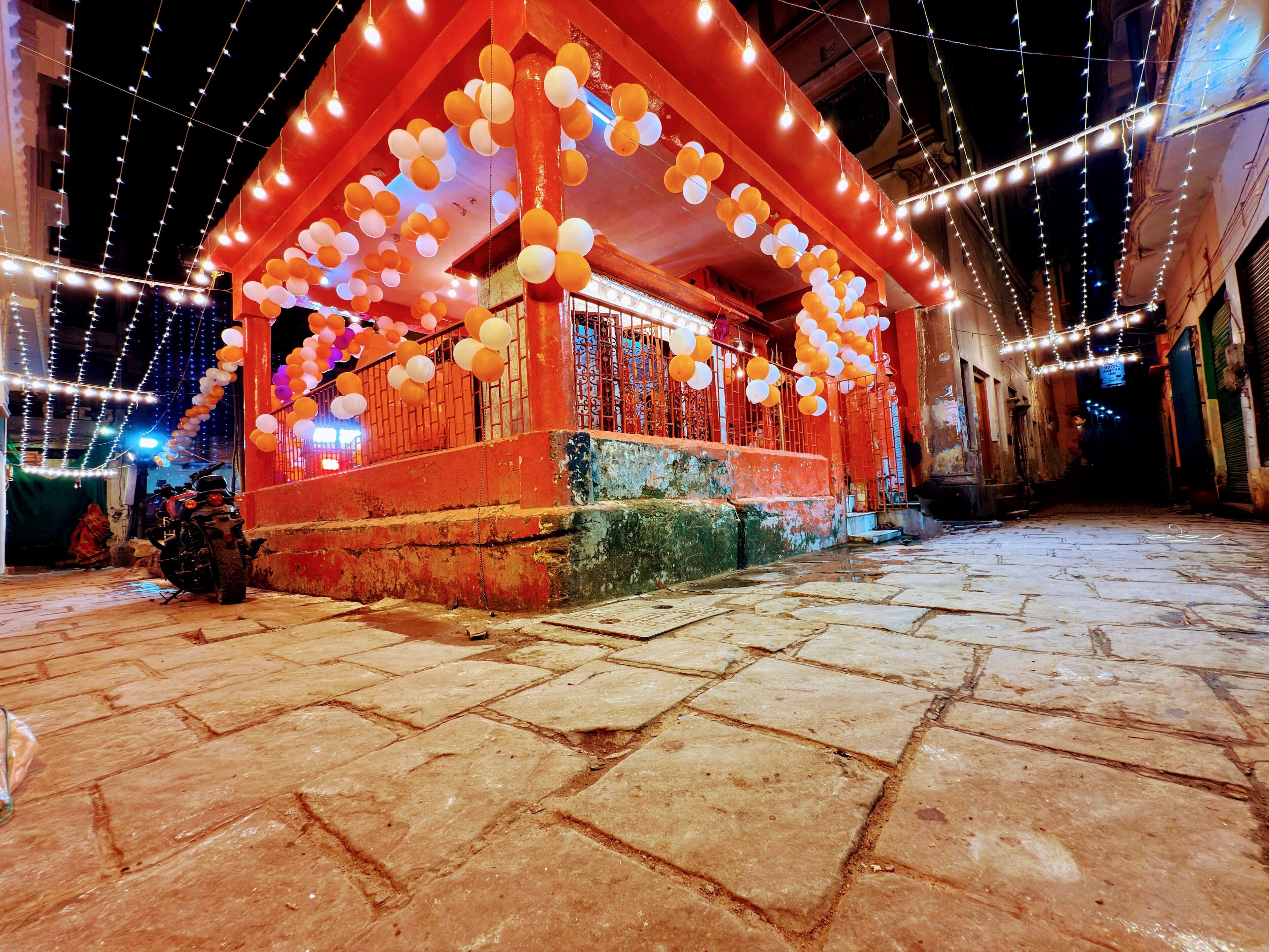 A building with a red exterior, stone steps, and string lights.