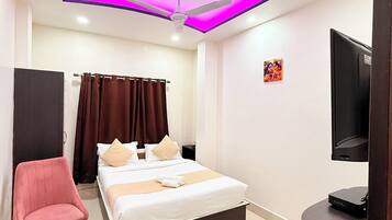 A modern hotel room with a bed, a chair, a television, and a ceiling fan.