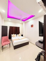Una habitación de hotel moderna con cama, una silla, televisor y ventilador de techo.