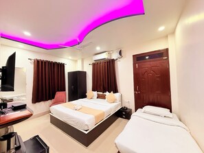 A hotel room with a bed, a desk, a wardrobe, and a door.