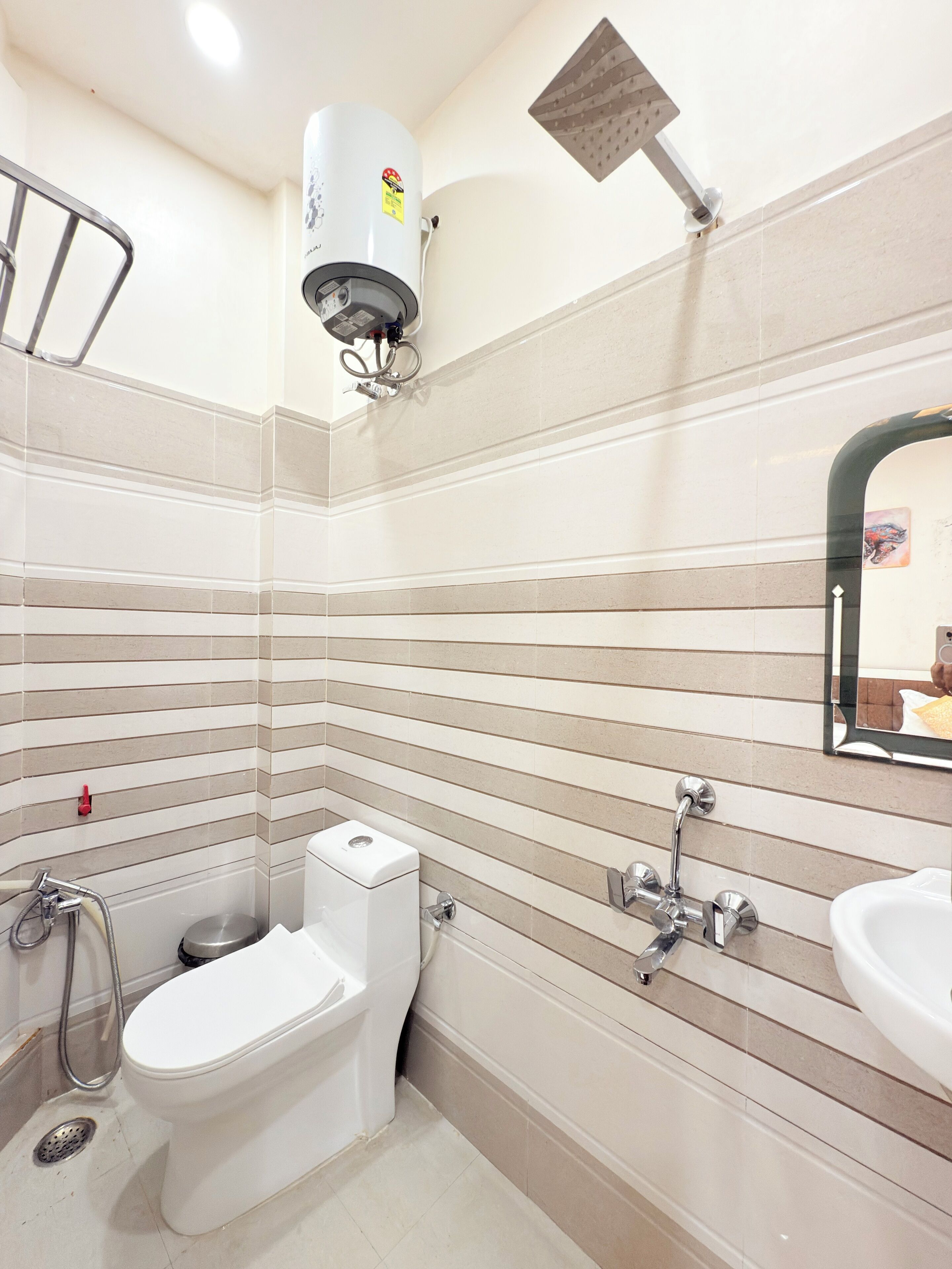 Une salle de bain équipée de toilettes, d’un bidet et d’une douche avec un pommeau de douche à effet pluie.