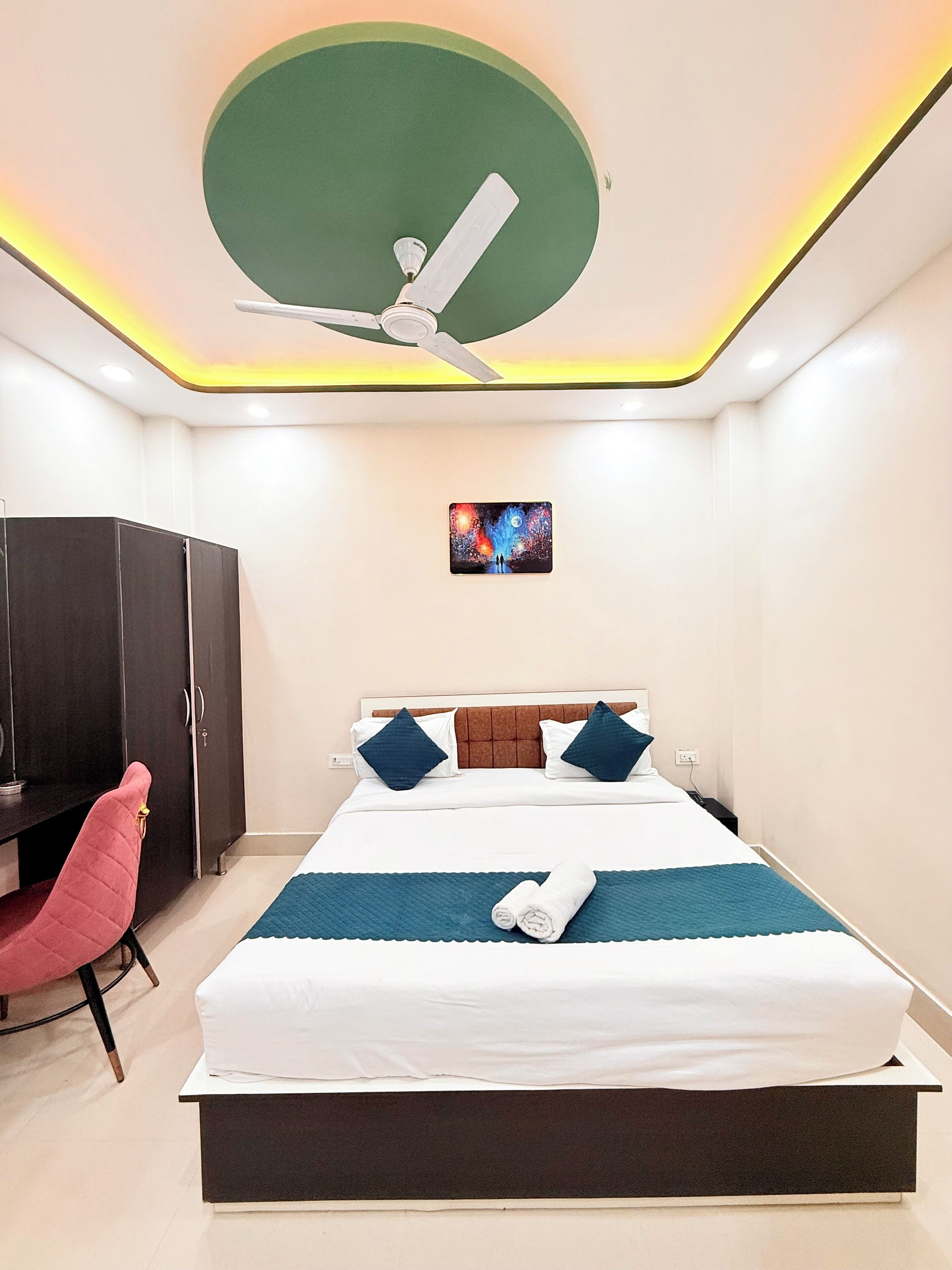 A modern hotel room with a bed, a desk, a chair, and a ceiling fan.