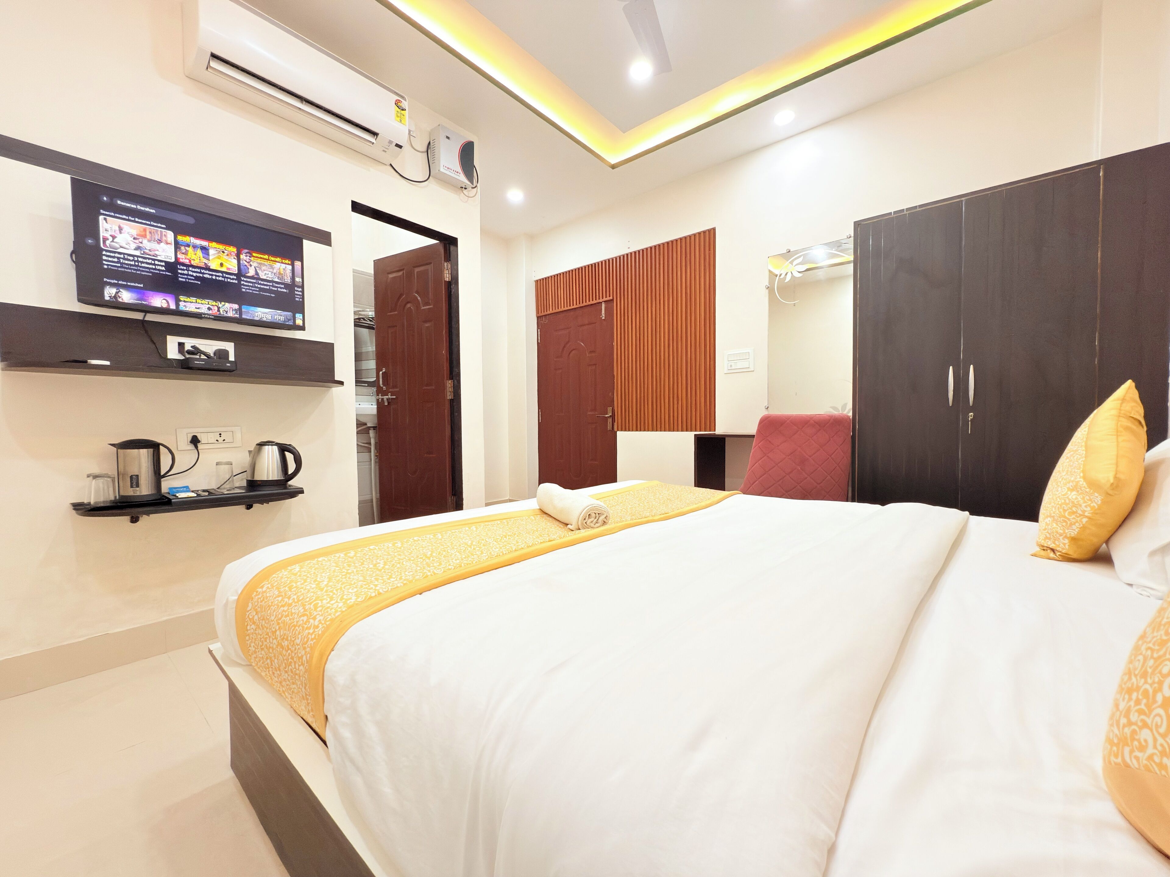 Una habitación de hotel con cama, televisor, armario y cafetera.