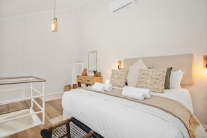 Una camera da letto moderna con un letto, un comodino, uno specchio e una lampada a sospensione.