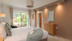 Une chambre à coucher avec un grand lit, une commode en bois, un miroir et une porte-fenêtre coulissante donnant sur un balcon.