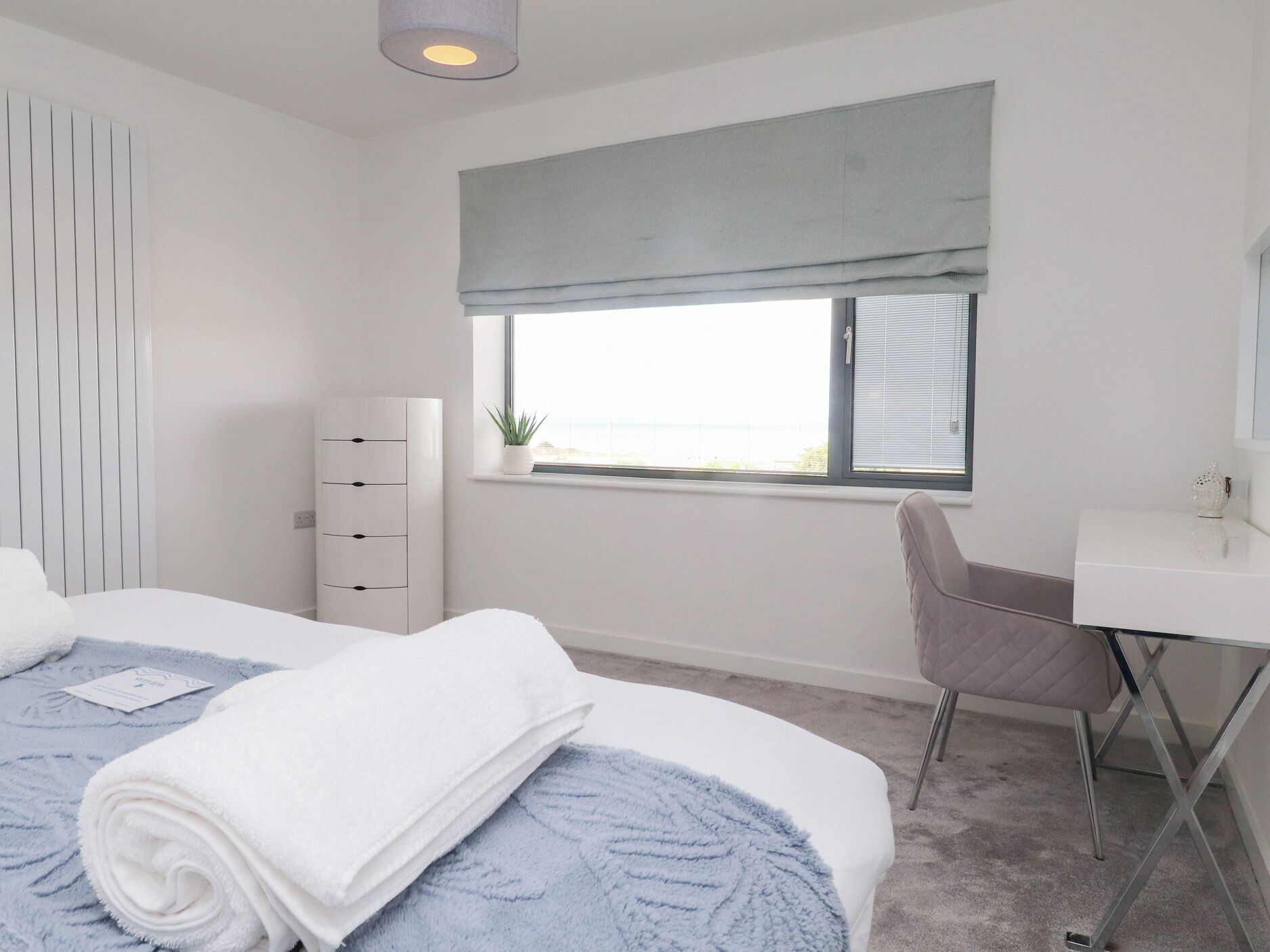 A modern bedroom with a bed, a desk, and a chair.