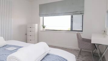 A modern bedroom with a bed, a desk, and a chair.