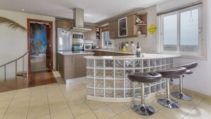 A modern kitchen with a central island, bar stools, and a view of the outside. - Penthouse with Jacuzzi, Sea & Volcano View (Costa Teguise)