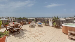 A rooftop terrace with a table and chairs, a hot tub, and potted plants. - Penthouse with Jacuzzi, Sea & Volcano View (Costa Teguise)