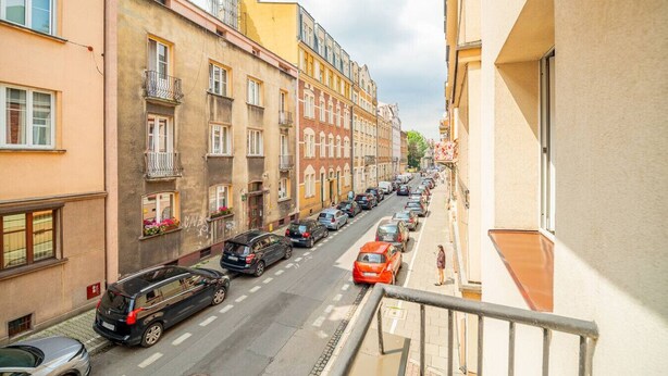 Vista callejera con coches estacionados y edificios a ambos lados.