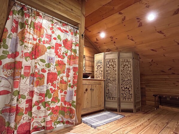 L’intérieur d’une cabane en bois, avec un rideau de douche à motifs, des armoires en bois et une porte décorative.