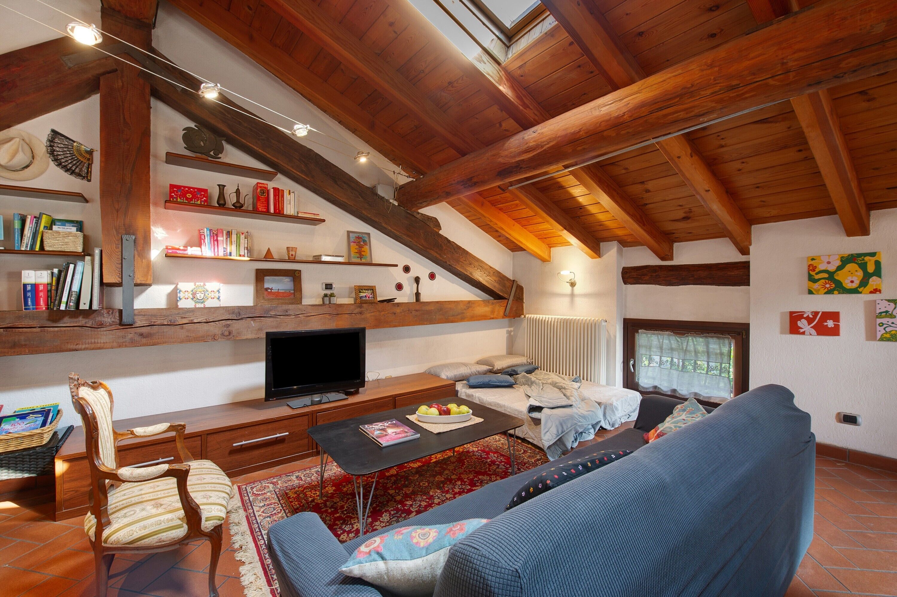 Una sala de estar acogedora con techo de madera, un televisor, un sofá, una mesa de centro y una estantería.
