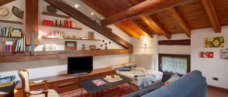 Una sala de estar acogedora con techo de madera, un televisor, un sofá, una mesa de centro y una estantería.