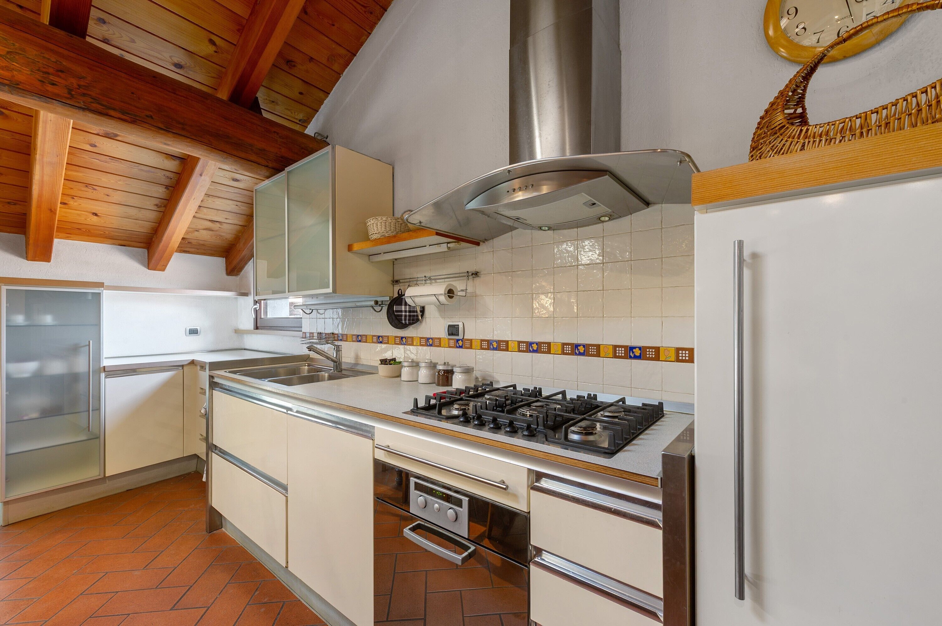 Een keuken met een gasfornuis, oven en een rvs afzuigkap.