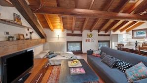 A cozy living room with a fireplace, sofa, and television. - 'The Traveler’s Attic' Apartment with Mountain View, Private Terrace and Wi-Fi (Pont Saint Martin)