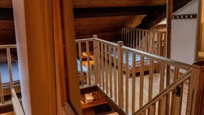 A wooden interior with a skylight, a staircase, and a view of a room below.