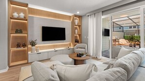 Un salon moderne doté d’un grand téléviseur à écran plat, d’étagères en bois intégrées, d’un canapé confortable et d’une porte en verre donnant sur un espace extérieur.