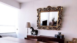 A dining area with a large wooden table and benches, a decorative mirror on the wall, and a lamp on a side table. - Apartment in the south of the city with everything for the family and very close to everything. (Ciudad de México)
