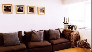 A living room with a brown sofa, a black rug, and four framed pictures on the wall. - Apartment in the south of the city with everything for the family and very close to everything. (Ciudad de México)
