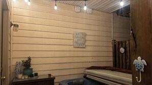 A room with a hot tub, wooden walls, a sign saying "SALTY, SANDY, AND Happy", and a turtle decoration.