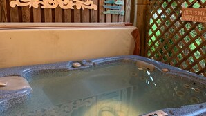 Un bain à remous avec une terrasse en bois et une pancarte sur laquelle on peut lire : « Ici, je suis heureux/heureuse. »