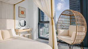Ein Schlafzimmer mit Bett, Schreibtisch, Stuhl und Blick auf die Stadtlandschaft.