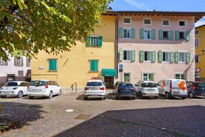 Fila de coches aparcados frente a un edificio con varias ventanas y un toldo verde.