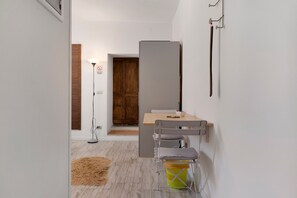 Una habitación moderna con puerta de madera, un escritorio con silla, una lámpara colgante y una lámpara de pie.