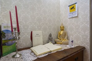 Une pièce comprenant une statue de Bouddha, un chandelier, un livre et un panneau indiquant la présence d’un système de vidéosurveillance.