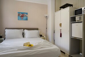A hotel room with a bed, a nightstand, a lamp, a wardrobe, and a painting on the wall.