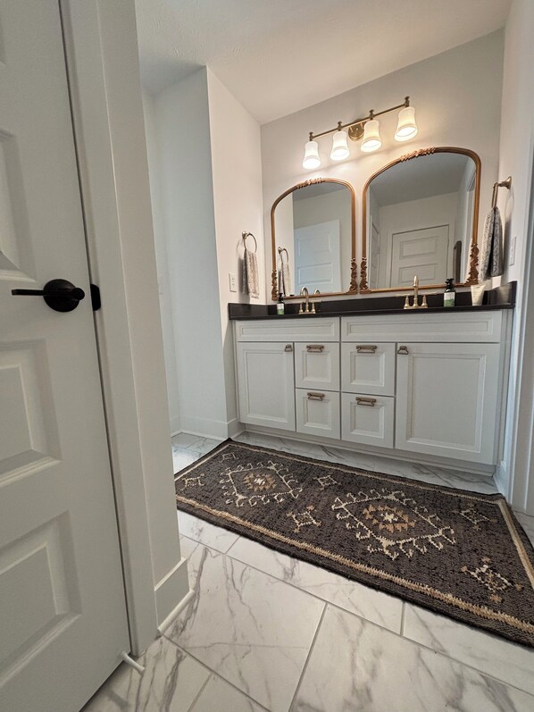 Un baño con un espejo grande, un lavabo y un mueble de tocador con cajones.