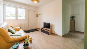 Ein modernes Wohnzimmer mit einer Couch, einem Fernsehschrank und Topfpflanzen.