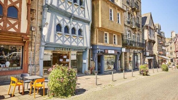 Eine Kopfsteinpflasterstraße gesäumt von historischen Gebäuden, darunter ein Geschäft mit dem Schild 'DEELLE'.