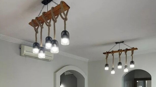 A modern living room with a sofa, round ottoman, and pendant lights. - Golden Square Resort (Riyadh)