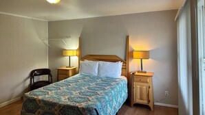 Une chambre à coucher avec un lit, deux tables de chevet avec des lampes, une chaise et une armoire en bois.
