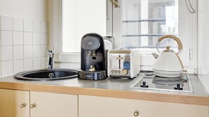 Une cuisine équipée d’un évier, d’une machine à café, d’un grille-pain et d’une bouilloire posés sur le plan de travail.