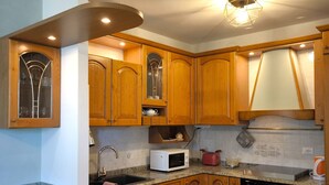 Une cuisine avec des meubles en bois, un plan de travail en granit, un four à micro-ondes encastré, un grille-pain et un évier.