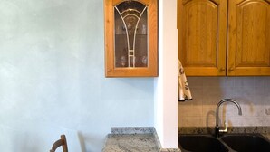 Une cuisine dotée d’un plan de travail en granit, de meubles en bois, d’un évier et d’un luminaire suspendu.