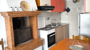 A kitchen with a marble fireplace, a gas stove, a sink, and wooden cabinets. - SG Family - Villa Secolo (Peschiera del Garda)