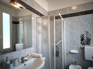 Ein modernes Badezimmer mit einer Duschkabine aus Glas, einem Waschbecken mit Spiegel und einer Toilette.