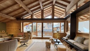 Un ampio soggiorno con soffitto in legno, ampie finestre e una zona salotto accogliente.
