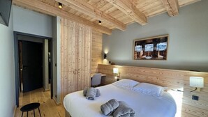 Una camera da letto con un letto grande, travi in legno a soffitto, una scrivania e una sedia.